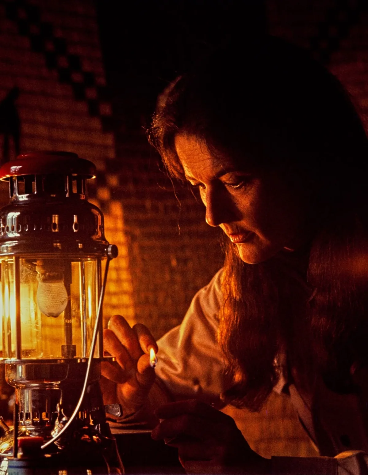 Dian Fossey, le visage éclairé par une lampe à pétrole qu'elle allume